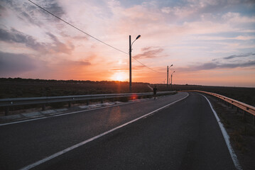 Attractive fit man running along modern bridge at sunset light,