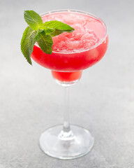Watermelon margarita cocktail with lime. Watermelon summer cocktail with ice and mint leaves. Cold refreshment drink in a glass with water drops. Low depth of field, selective focus.
