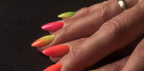 Kolorowe paznokcie przedstawione z bardzo bliska, na ciemnym tle