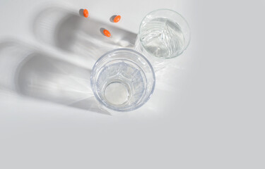 A glass of clean water with natural vitamins, with shadows on a light background. Flat lay