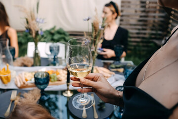 Woman holding a white wine glass, close-up, at a party, outdoors.