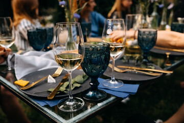 Glasses of water and wine placed on a table at an open air party. Luxury table arrangement with golden cutlery.