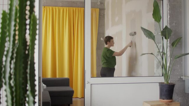 DIY home repair in self-isolation in quarantine Woman worker paint wallboard walls in her room