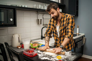 Young man is making cookies in his kitchen. He hates cooking.