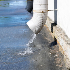 A stream of water pours down the drainpipes from the roofs of houses.