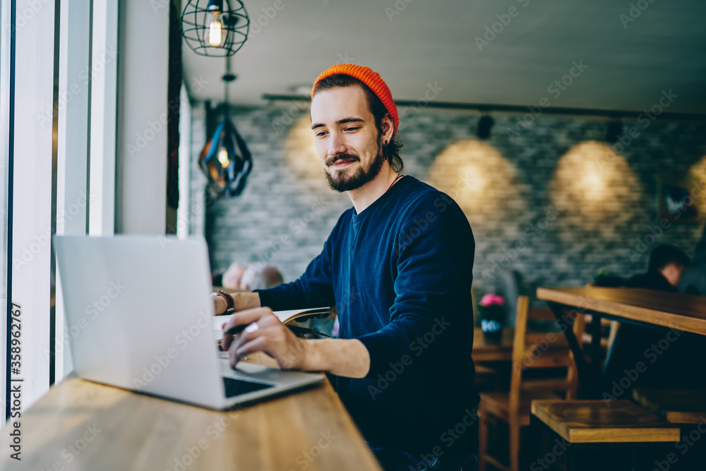 Wall mural positive caucasian male checking news from networks working remotely on publicity area, man freelanc