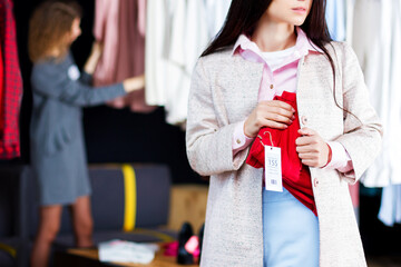 Closeup of young woman is stealing red jeans in store, shop, boutique at shopping center. Girl is...