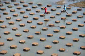 Children playing jump in the dam
