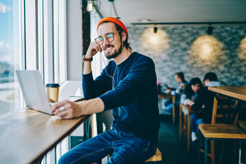 Happy smiling hipster guy i classic glasses enjoying time for favourite music playlist during e...