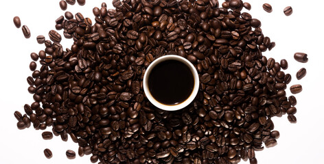 A small cup of coffee with coffee beans on white background. Top view