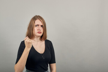 Angry and aggressive, shaking fist in a threatening way, domestic violence. Young attractive woman,...
