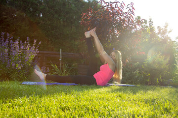 Healthy lifestyle concept. Young woman does a work-out during sunset. Greenery and grass help to...