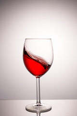 A splash of red wine in a glass on a white background