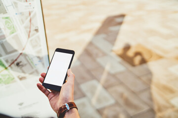 Cropped image of male hand holding smartphone with mock up screen copy space area for advertising, blank mobile phone application for navigating in city via 4G connection and online gps maps