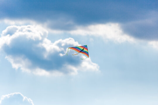 A large multicolored kite on a bright blue sky on a Sunny day. Bright toy for children