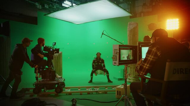 In the Big Film Studio Professional Crew Shooting Blockbuster Movie. Director Commands Cameraman to Start shooting Green Screen CGI Scene with Actor Wearing Motion Tracking Suit and Head Rig