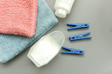 Flat lay composition with clean towels, clothespins and measuring scoop of laundry powder on gray background.