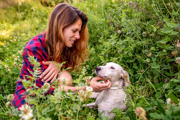 Young woman with her dog in a field of flowers