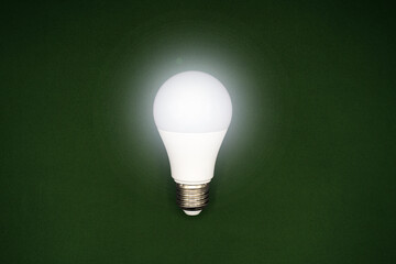 Successful idea concept. Creativity and innovation. Isolated light bulb glowing on dark green background.