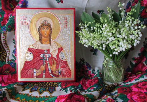 Traditional orthodox icon of St. Barbara. Handwritten icon on the background of Ukrainian rushnyks and lilies of the valley. Faith and Christianity. Photof an modern icon of the Ukrainian icon painter