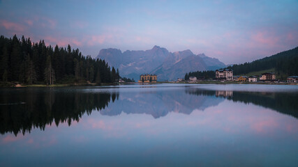 Reflection of seamless calm and still lake in Misurina, Italy with yellow building in front of mountains