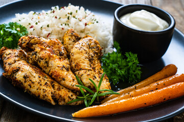 Steamed chicken nuggets, rice and small carrots on wooden table
