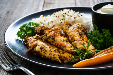 Steamed chicken nuggets, rice and small carrots on wooden table
