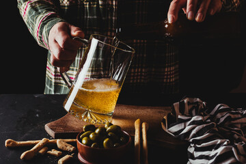 Close-up of a waitress serving beer with a large glass pitcher in a dark, rustic setting.