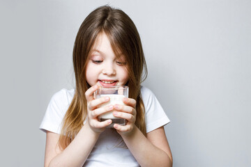 A baby girl looks happily at the glass of milk