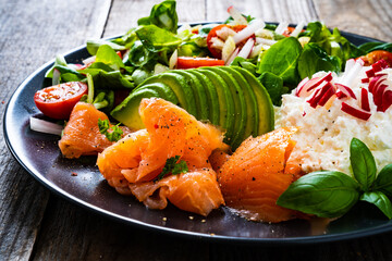 Breakfast - smoked salmon, cottage cheese, avocado and vegetable salad on wooden table