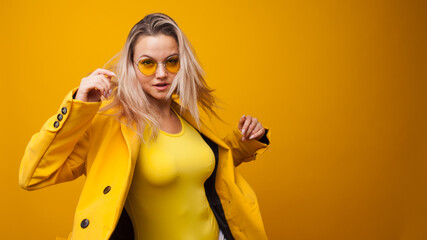 Stylish bright young woman dancing and rejoicing. The girl in the yellow jacket