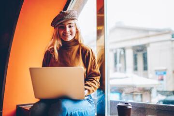 Portrait of cheerful female freelancer satisfied with successful online business working on free...