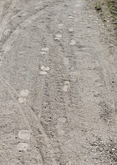Human footprints and tire trucks on the dusty ground / pathway / footpath in the forest / on the field 