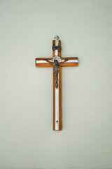Small wooden  / matal cross hanging on light pastel background in old vintage house