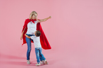 Mom is a superhero. happy family, a young blond woman in a red Cape and her son jumps and takes of