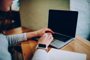 Cropped image of female freelancer using laptop computer for searching information and browsing...
