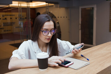 The girl in the coworking works online, a young business woman with glasses uses voice input