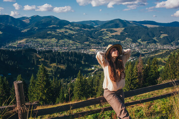 Fototapeta na wymiar a girl in a hat with long hair resting in the mountains. She has a view of the mountains behind her. view of the Carpathians