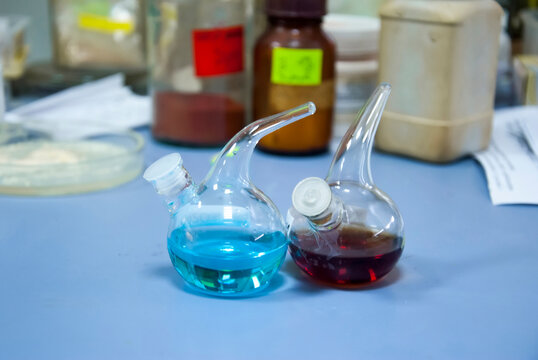 Two glass flasks with liquid chemicals prepared for chemical reaction, in a laboratory