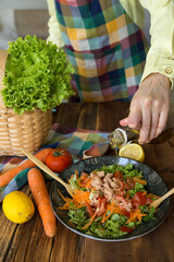 Making salad with tuna, lettuce, carrot, tomato, arugula, cucumber, olive oil, lemon.