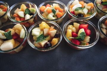 Top view of small glass dishes with fruit salad. Colorful fresh fruit cut to small pieces for refreshment. Party, birthday or wedding concept.