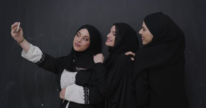 Beautiful muslim women in fashionable dress with hijab using mobile phone over chalkboard backgorund