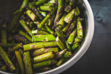 Juicy mouth-watering photo of chopped and seasoned green asparagus ready to cook