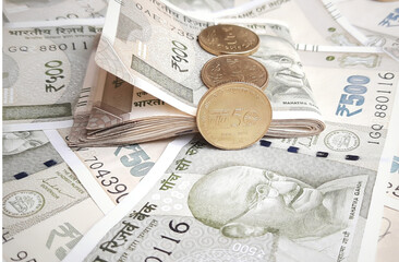 New Indian 500 rupees currency notes spread randomly and 500 rupees notes with rubber band with 5 rupee coins in white paper