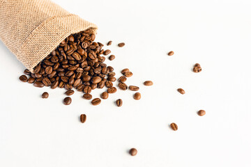 A burlap bag with coffee beans on a white, scuffed background. Concept of a popular invigorating drink. selective focus.