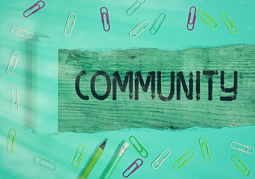 Conceptual hand writing showing Community. Concept meaning group of showing with a common characteristics living together Rolled ripped torn cardboard above a wooden classic table