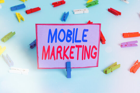 Writing note showing Mobile Marketing. Business concept for advertising that promotes products via adaptable devices Colored clothespin papers empty reminder blue floor officepin