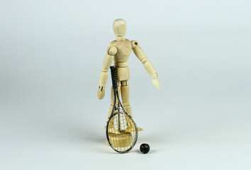 Wooden mannequin with tennis racket. Light background