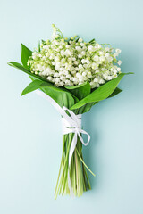 lily of the valley flowers bouquet on pastel blue background. flat lay. top view. wedding background. vertical orientation