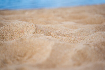 Fototapeta na wymiar Close up of sand shore with blurred sea background.